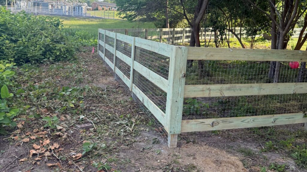A split-rail fence with wire mesh installed in a backyard by Superior Fence & Rail of Charlotte, NC