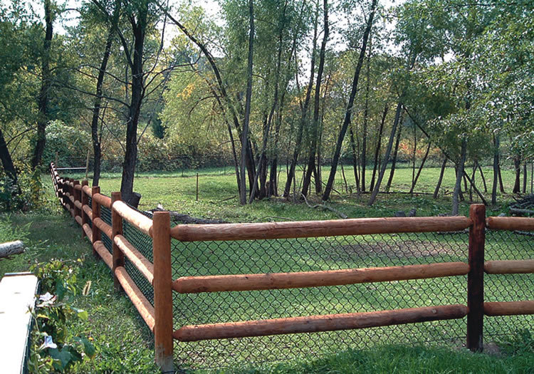 A long split-rail fence with wire mesh installed in a natural, rural setting by D-Fence of Tulsa in Tulsa, OK.