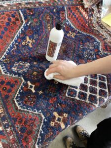 A hand spot cleaning an oriental rug with a specialized cleaner at Renaissance Rug Cleaning Inc. in Portland, OR.
