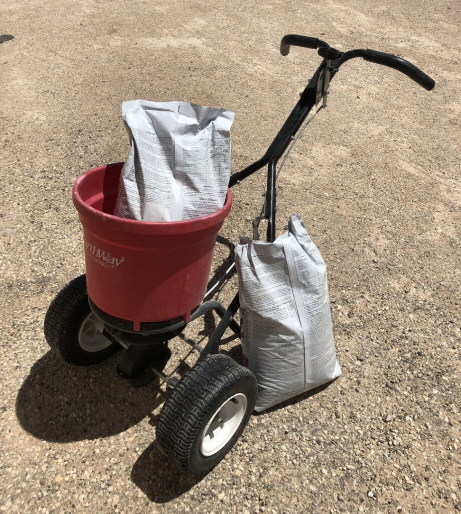 A push spreader with bags of product, ready for weed control application by Horizon Pest Control in Carlsbad, NM.
