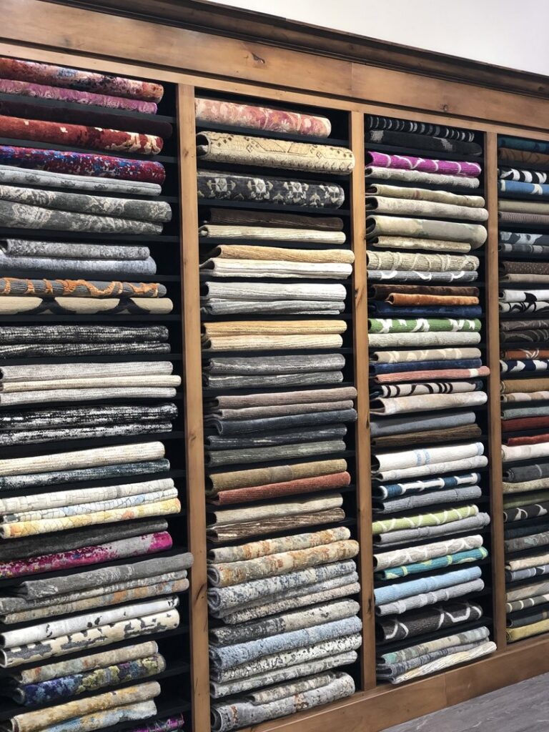 A large stack of colorful, intricately patterned rugs in the Organic Looms showroom in Scottsdale, AZ