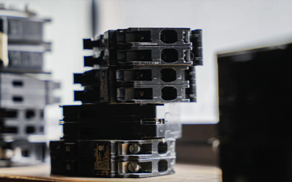 A stack of various circuit breakers, essential components for electrical panel work by Mister Sparky NWA in Springdale, AR.