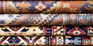 A neatly stacked pile of clean and restored patterned rugs at George Bell Rug Cleaning & Restoration in Jackson, MS.