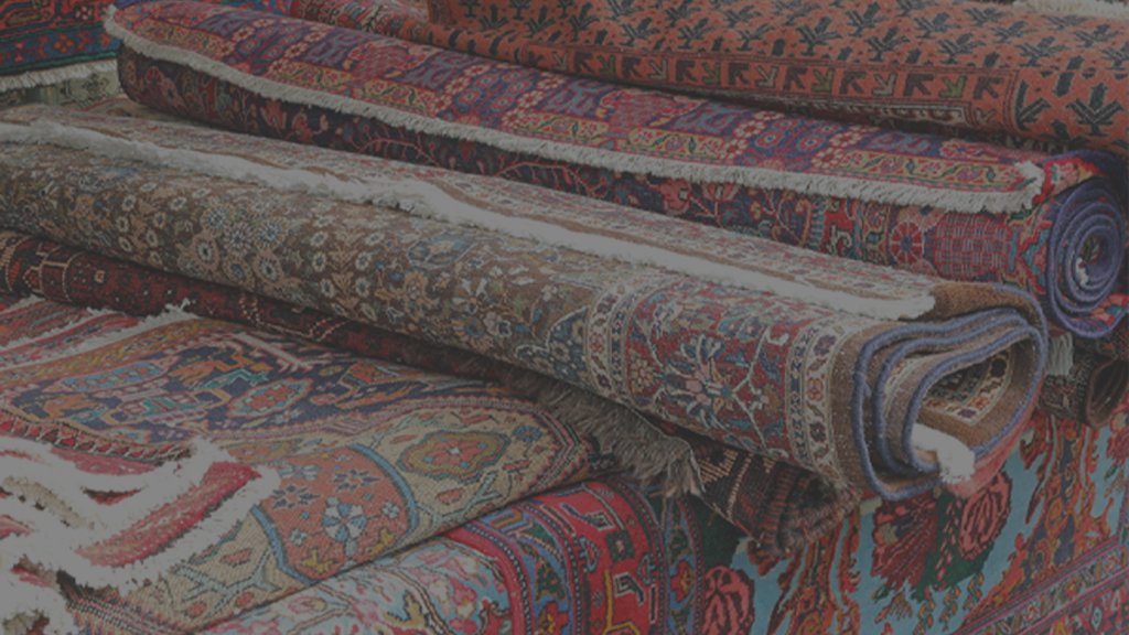 A stack of beautifully rolled oriental rugs, ready for service at Duke Brothers Oriental Rug Cleaning in Norfolk, VA.