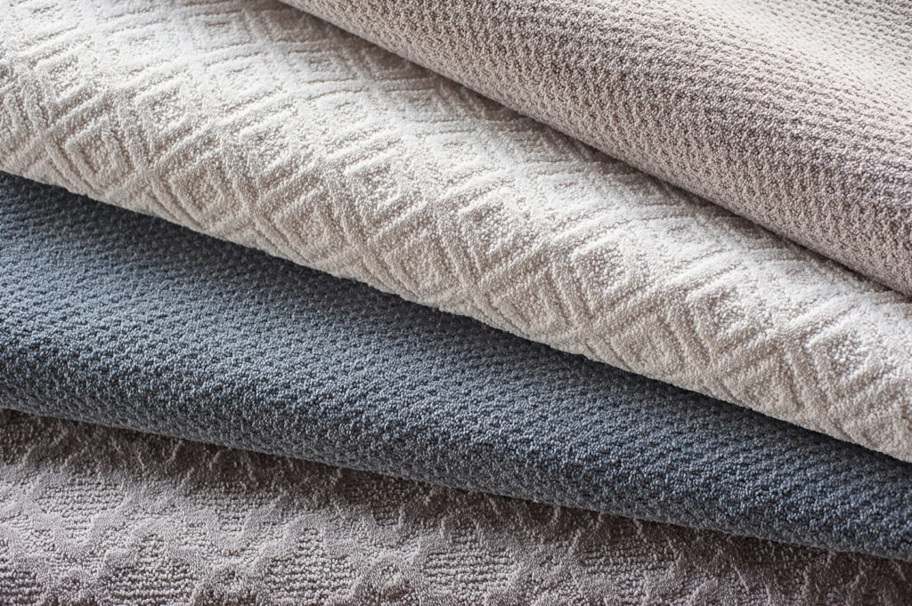 A close-up view of a stack of various carpet samples available at Junge's Flooring in Rochester, MN
