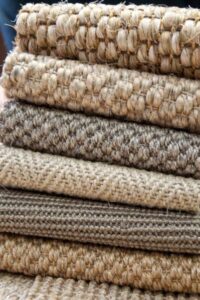 A stack of various textured carpet and rug samples, demonstrating materials available from Odino Designs, llc in Portland, OR.
