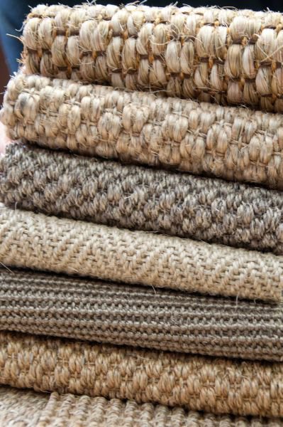A stack of various textured carpet and rug samples, demonstrating materials available from Odino Designs, llc in Portland, OR.