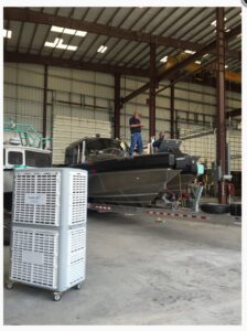 Stacked evaporative coolers providing cooling in a large warehouse with a boat by Cajun Kooling in Broussard, LA