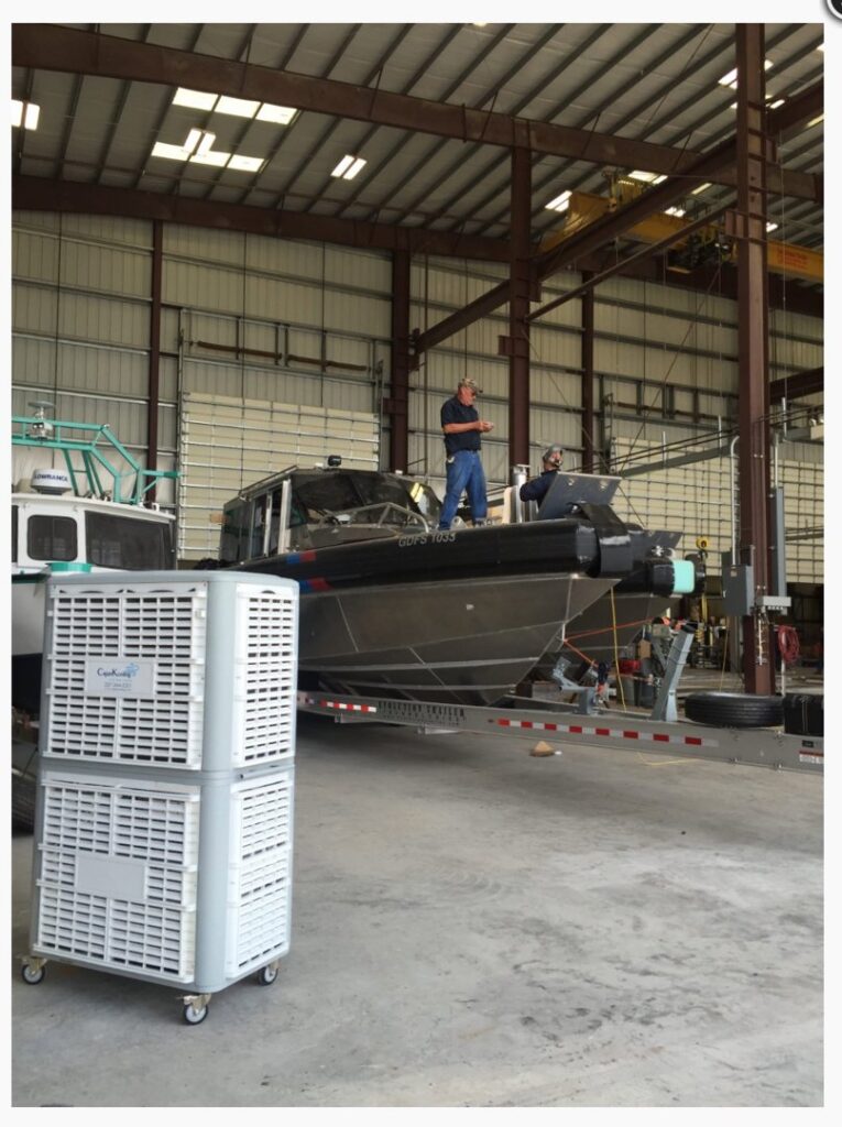 Stacked evaporative coolers providing cooling in a large warehouse with a boat by Cajun Kooling in Broussard, LA