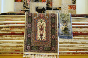 A colorful display of stacked patterned rugs and a hanging patchwork rug, representing the selection at Carpet Cleaner Staten Island in Staten Island, NY.