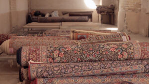 Stacked rolled carpets and rugs on shelves in a storage area, indicating inventory for Carpet Cleaner Staten Island in Staten Island, NY.