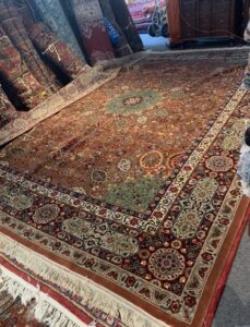 Numerous rugs stacked and rolled in a storage or workshop area at Danvers Rug in Danvers, MA.
