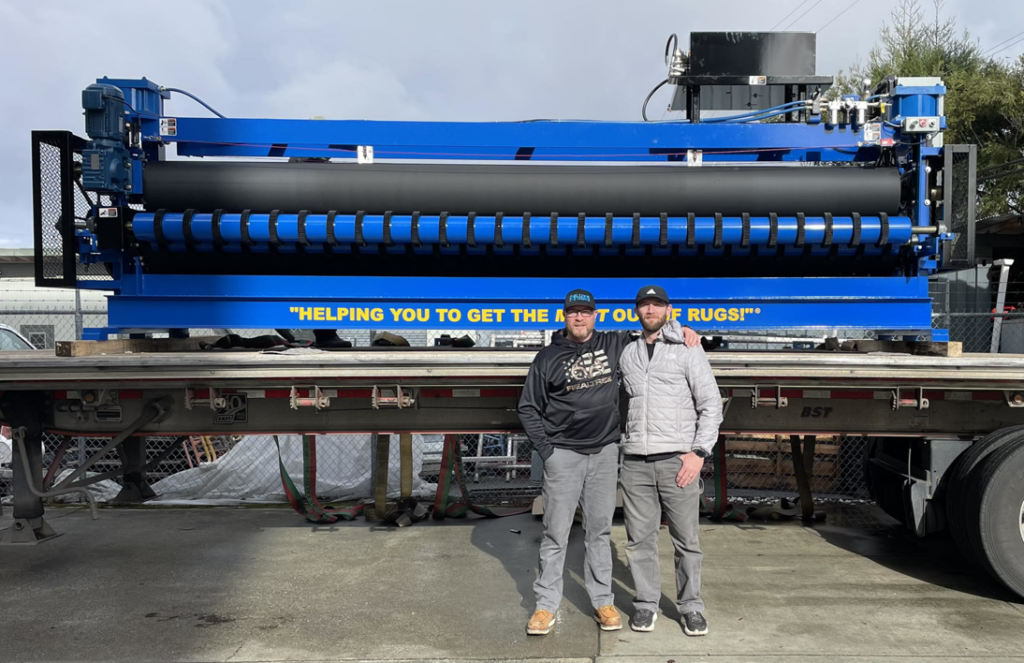 Two staff members standing with a large industrial rug cleaning machine at Deluxe Dye Works in San Jose, CA.