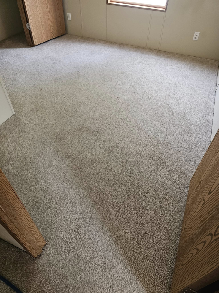 A stained carpet in a room before professional cleaning by Peterson's Carpet & Air Duct Cleaning in Dickinson, ND.