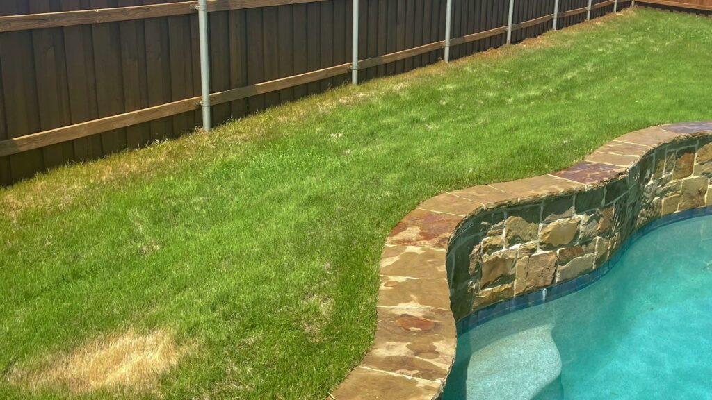 A newly stained wood fence bordering a swimming pool area by Texas Tuff Stain and Seal in Fort Worth, TX.