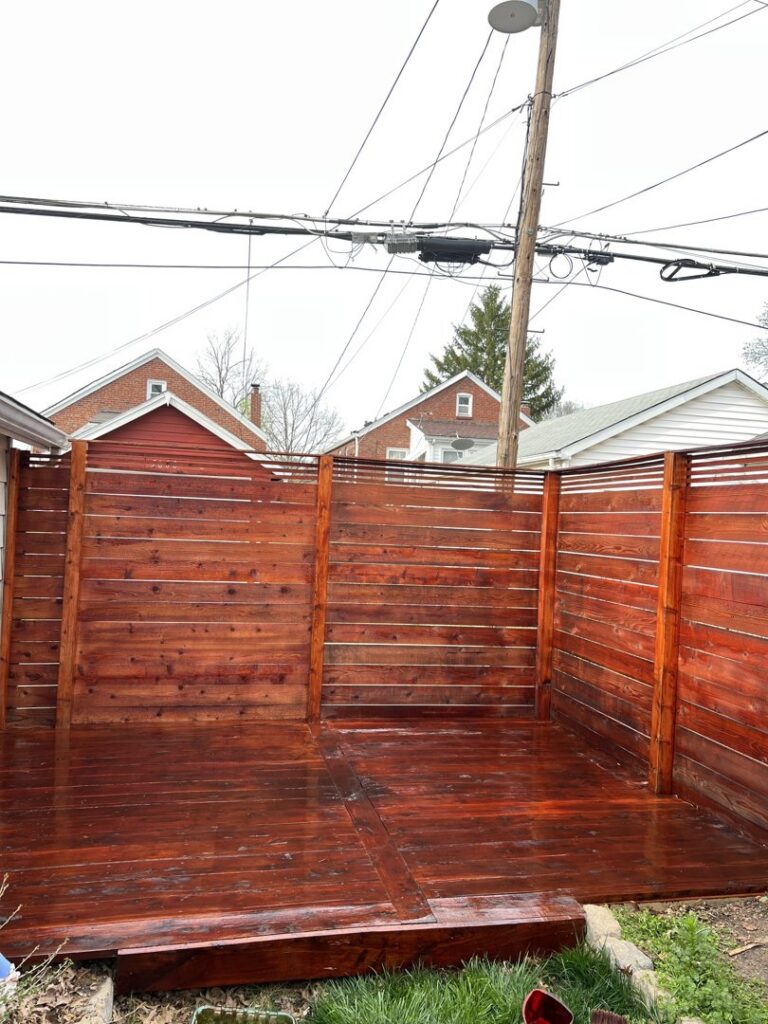 A newly stained horizontal wood fence and matching deck, showcasing work by Exterior Experience LLC in St. Louis, MO.