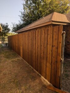 A newly stained vertical wood privacy fence installed by Pro Insulation and Fence in Wichita Falls, TX.