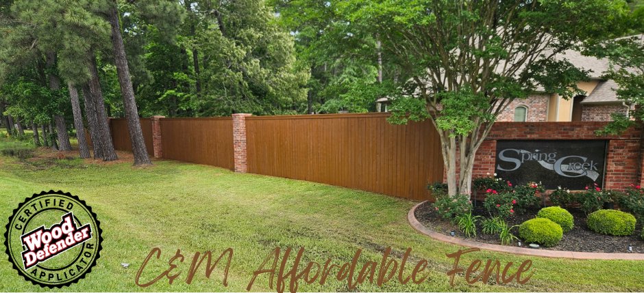 A long, stained wood fence with decorative brick pillars at a community entrance, installed by C & M Affordable Fence, LLC in Haughton, LA