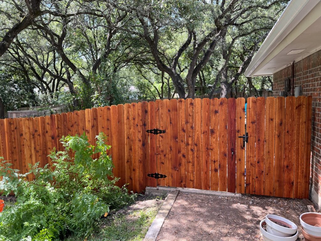 A beautiful stained wood picket fence with a gate installed by Good Neighbor Fencing and Construction in Austin, TX.