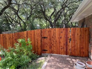 A beautiful stained wood picket fence with a gate installed by Good Neighbor Fencing and Construction in Austin, TX.