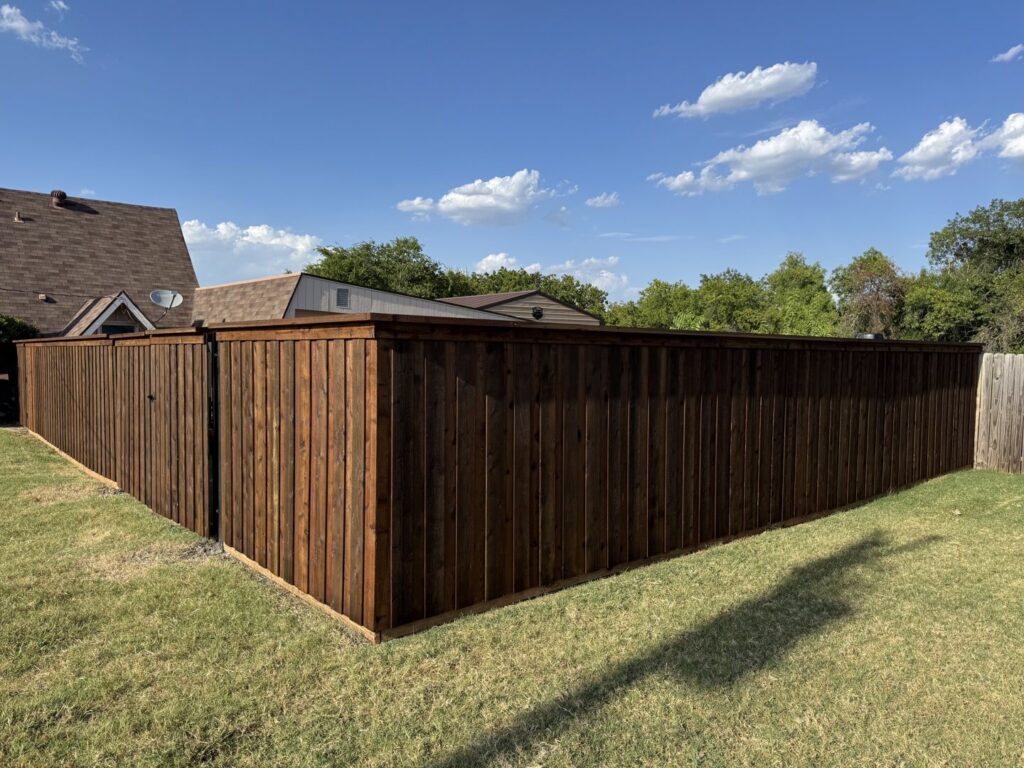 A dark stained wood privacy fence with a corner section in a residential yard by Dallas Fence in Dallas, TX.