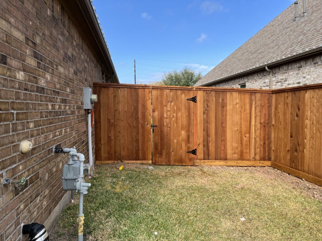 A beautifully stained wood privacy fence with a double gate, expertly installed by Fence Builders of Houston, TX.