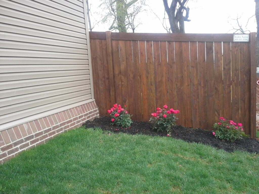 A newly installed stained wood privacy fence next to a residential home by Border Built Fencing in Florence, KY.