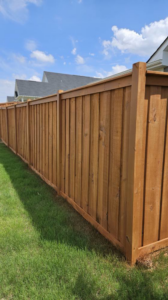 A beautifully stained brown wood privacy fence installed in a green lawn by The Fence Guy One in Greenville, SC.