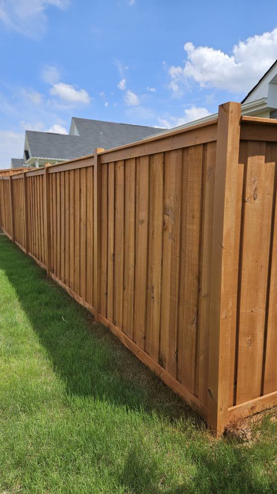 A beautifully stained brown wood privacy fence installed in a green lawn by The Fence Guy One in Greenville, SC.