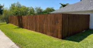 A beautifully stained wooden privacy fence lining a residential property, installed by JH Fencing in Lawrence, KS.