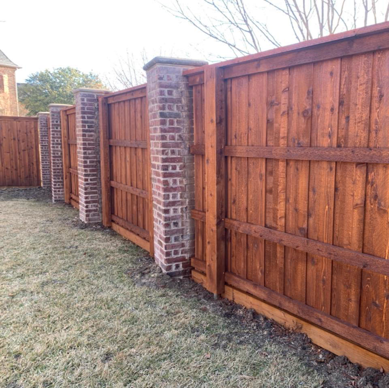 A stained wood privacy fence featuring sturdy brick posts, installed by 3M Custom Fence in Lewisville, TX.