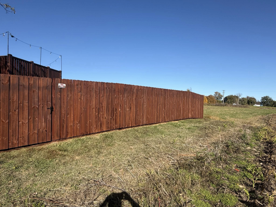 A newly installed stained wood privacy fence with a gate by Quality Deck & Fence LLC in Owensboro, KY