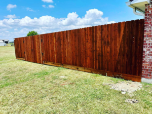 A newly installed stained wooden privacy fence next to a brick house, completed by HammerHorn Fence & Gate Systems in Rochelle, IL.