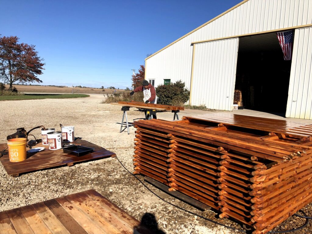 A worker staining wood fence panels for a project by Cedar Mountain Fence Company in Plainfield, IL.