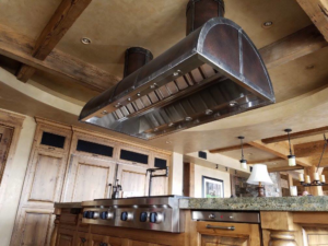 A large custom stainless steel and copper range hood installed over a kitchen island by Bensley Sheet Metal in Bozeman, MT.
