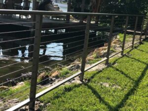 A modern stainless steel cable railing installed along a waterfront property by Fencing & Railing 2 Corp in Orlando, FL.