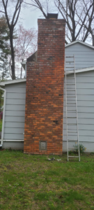 A newly installed stainless steel chimney pipe extending from the side of a house, installed by Carl's Hearth Services in Feura Bush, NY.
