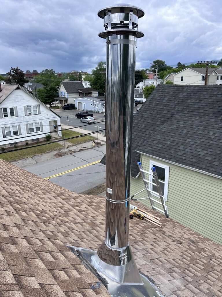 A newly installed stainless steel chimney liner and cap on a roof by Granite State Chimney in Manchester, NH