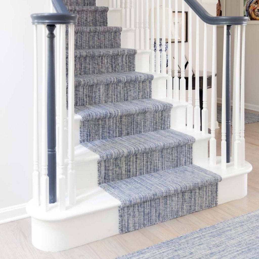 A beautiful staircase with a blue carpet runner professionally installed by Flooring Warehouse Houston, TX