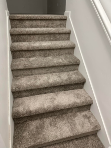 A staircase with new grey carpet professionally installed by Millennium Flooring .Co in Salt Lake City, UT.