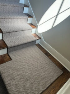 A newly installed light grey patterned carpet runner on a staircase by Elite Flooring America in Decatur, AL.