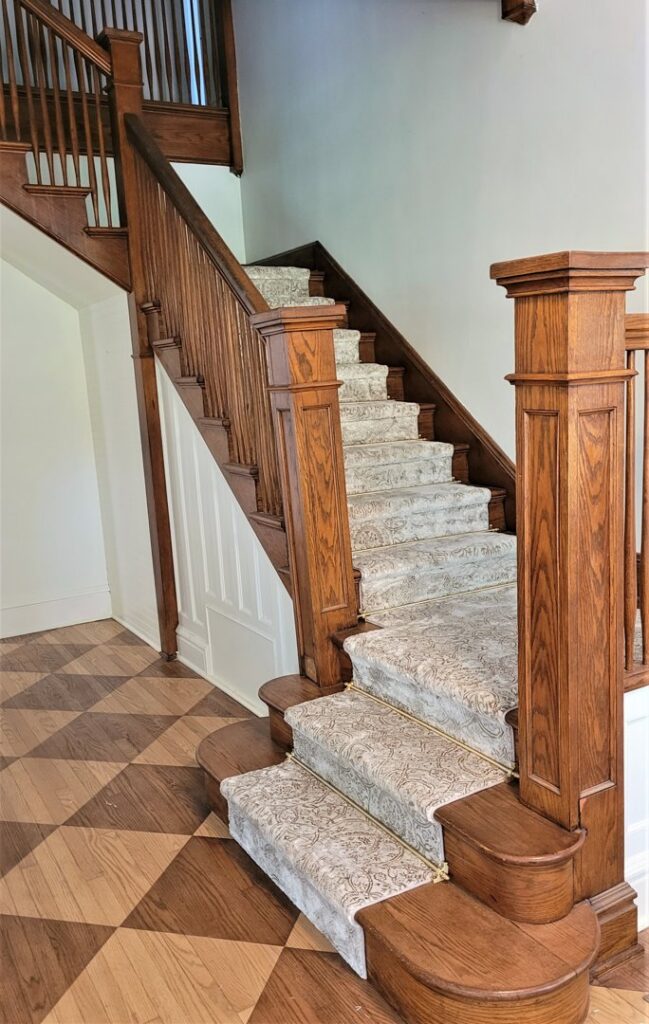 An elegant wooden staircase featuring a newly installed patterned carpet runner by The Carpet Shoppe in Springfield, MO.