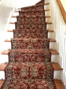 A beautifully installed patterned carpet runner on a wooden staircase by The Floor Pavilion in Concord, NC
