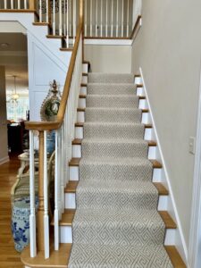 A patterned carpet runner professionally installed on a wooden staircase by Tile Town Carpet One in Syracuse, NY
