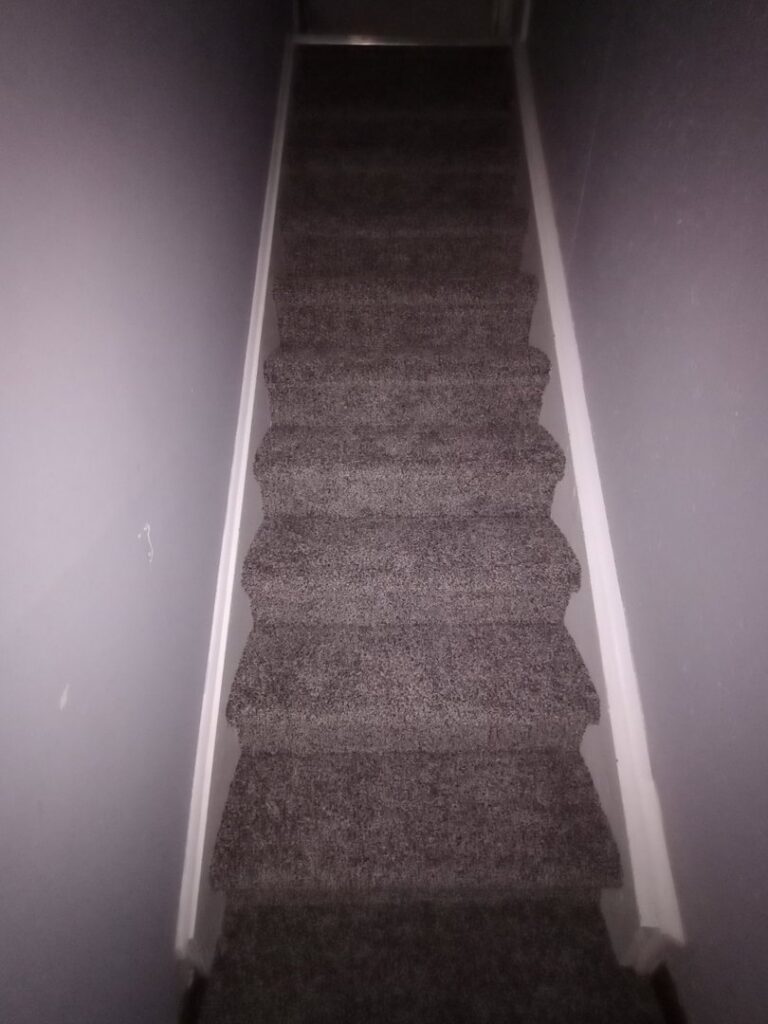 A staircase with new brown carpet installation, viewed from above, by Carpet Warehouse Lorain LLC in Lorain, OH.