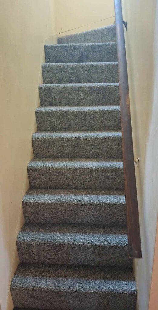 A staircase featuring newly installed grey carpet by PerfectStep Flooring Solutions in Rochester, NY.