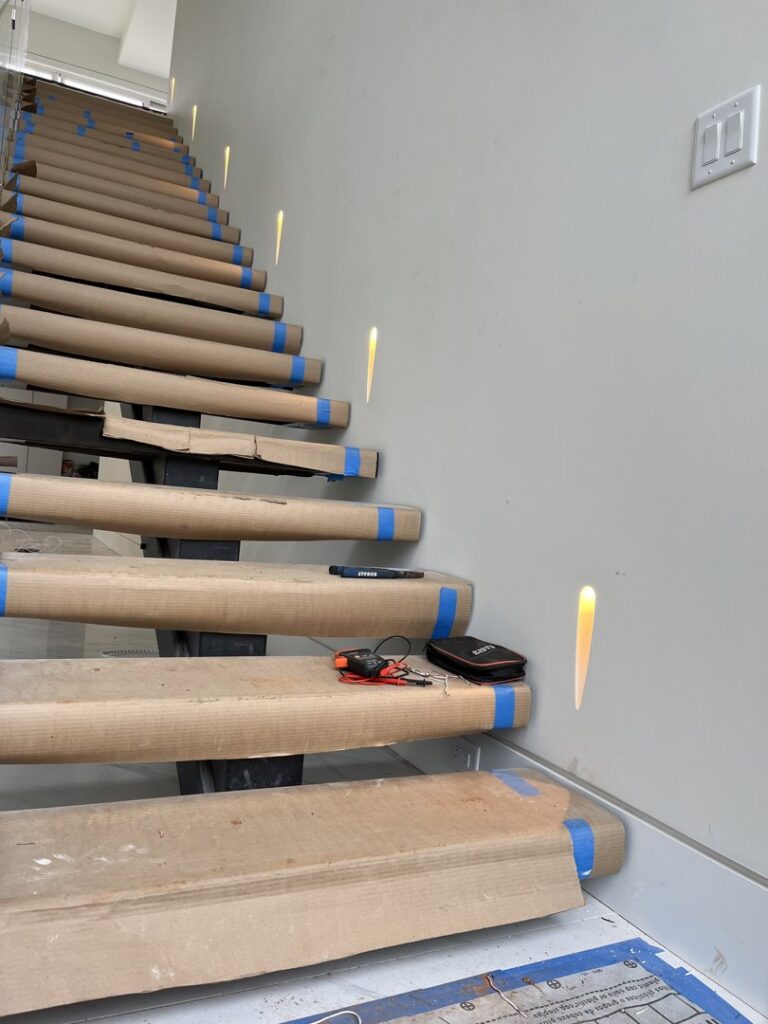 Staircase with modern recessed wall lighting and an electrician's tool, installed by Hilman Electric LLC in Greenville, SC.