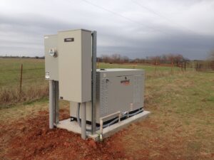 A standby generator and large electrical panel installed in a rural area by Generator Experts of Oklahoma in Norman, OK.