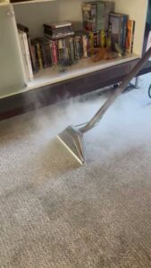 Steam carpet cleaning in progress, with a cleaning wand emitting steam over the carpet, by 303 Carpet Cleaning in Lakewood, CO