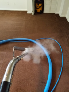 Steam carpet cleaning in progress on a brown carpet by Green Steam Carpet Clean in Portland, OR, showing active steam.